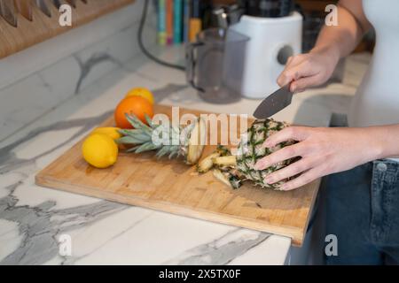 Woman slicing fruit in kitchen, close up Stock Photo