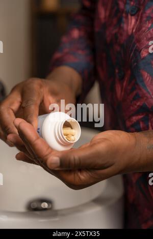 Man taking pills while standing next to bathroom sink Stock Photo