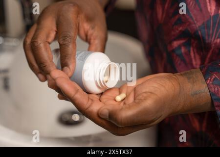 Man taking pills while standing next to bathroom sink Stock Photo