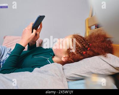 Girl lying on bed and using smart phone Stock Photo
