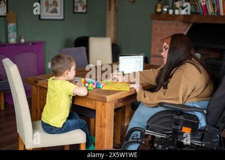 Woman on wheelchair sitting at table with son Stock Photo