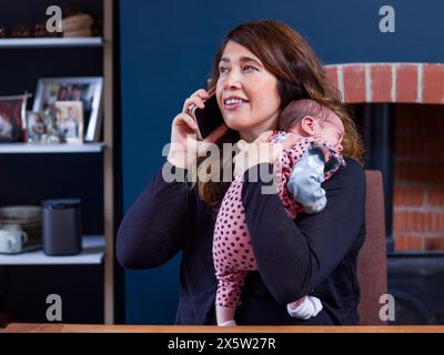 Woman with baby son  talking on smart phone at home Stock Photo