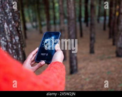Female hiker using compass on smart phone Stock Photo