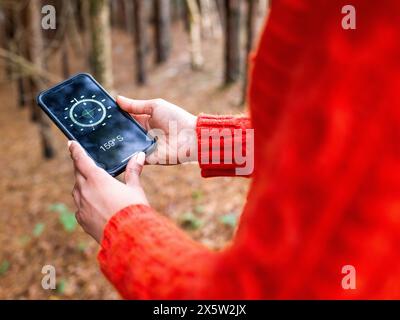 Female hiker using compass on smart phone Stock Photo