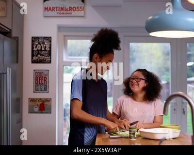 Sisters cutting vegetables in kitchen Stock Photo