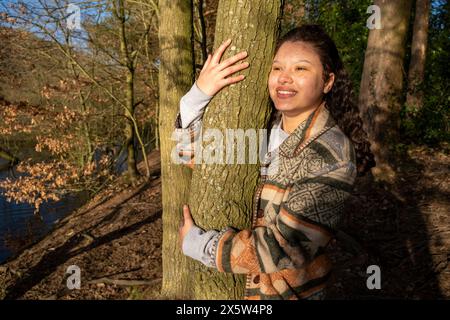 Smiling young woman hugging tree Stock Photo