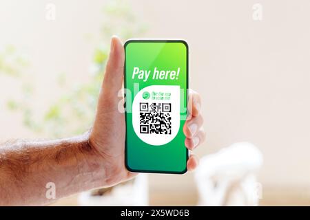Hand of man showing mobile smartphone with Qr code on the screen. Qr code payment, Cashless technology, Digital money concept. Stock Photo