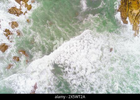 foam from waves breaking on a rocky coast, aerial overhead view with drone Stock Photo