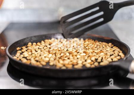 Traditional roasting of green beans in a cast iron pan. Aromatic coffee is made from fresh roasted beans. Selected focus. High quality photo Stock Photo