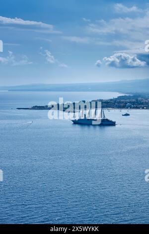 Italy, Sicily, Taormina, view of the eastern sicilian coastline and Giardini Naxox bay with a cruise ship Stock Photo