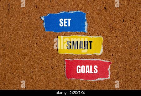 Set smart goals words written on ripped paper pieces with brown background. Conceptual set smart goals symbol. Copy space. Stock Photo