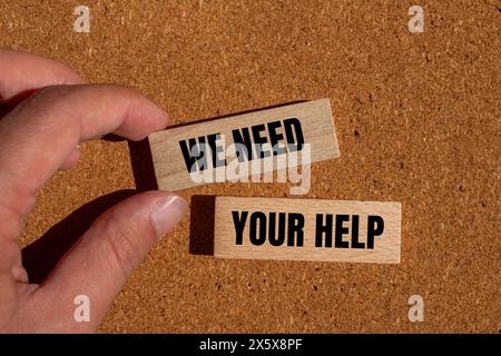 We need your help words written on wooden blocks with brown background. Conceptual we need your help symbol. Copy space. Stock Photo