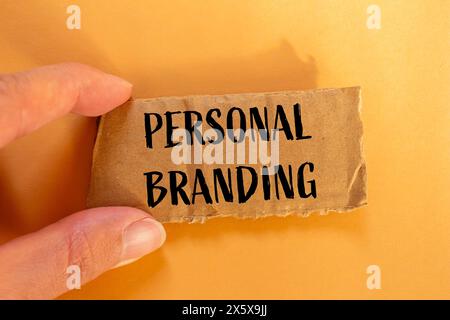 Personal branding words written on ripped cardboard paper piece with orange background. Conceptual personal branding symbol. Copy space. Stock Photo