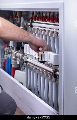 Plumber work. Installing collector for warm water underfloor heating system. Stock Photo