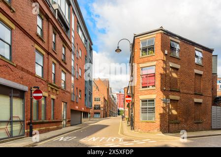 Cobbled street lined with old brick buildings converted into apartments and lofts and new block of flats in a central district on a sunny summer day Stock Photo