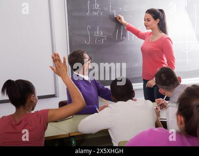 Cute student girl solves task near blackboard Stock Photo