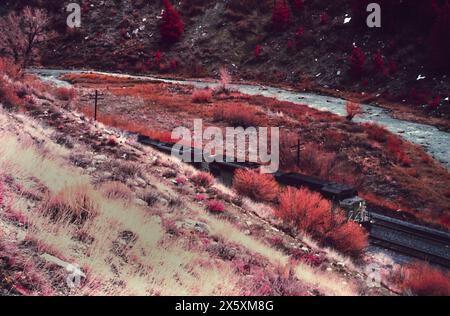 Freight train emerges from a steep grade around a beautiful mountain pass near the Spanish Fork River in Utah. Stock Photo