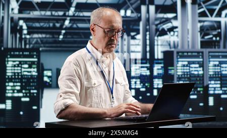 Certified technician expertly managing data while navigating in industrial server room. Professional ensuring optimal cybersecurity protection, optimizing systems and performing necessary updates Stock Photo