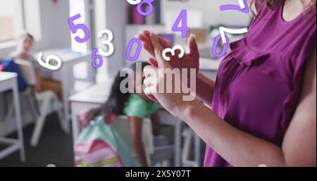 Image of numbers moving over happy biracial female teacher explaining to diverse school class Stock Photo