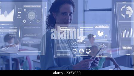 Image of data processing over happy diverse female teacher using tablet in school classroom Stock Photo