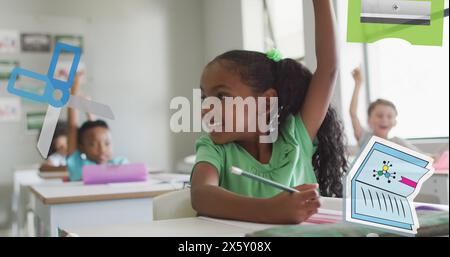 Image of school equipment over happy biracial schoolgirl raising hand in diverse class Stock Photo