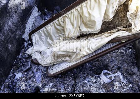 Burnt coffin wit0h flowers in cemetery, religion and burial Stock Photo