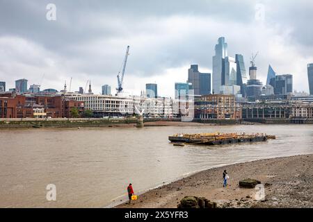 River Thames at low tide with people walking along the bank of the Thames, city of London skyline in the distance,London,England,2023 Stock Photo