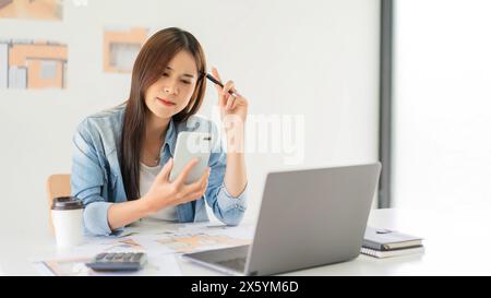 Construction design concept, Female architect using smartphone during thoughtful about house plan. Stock Photo