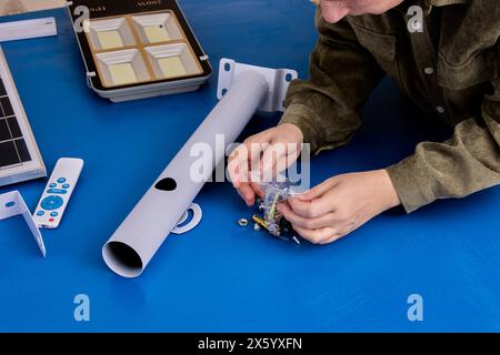 Installing holder for solar panel and LED street lamp, assembler unpacks package with fasteners. Stock Photo