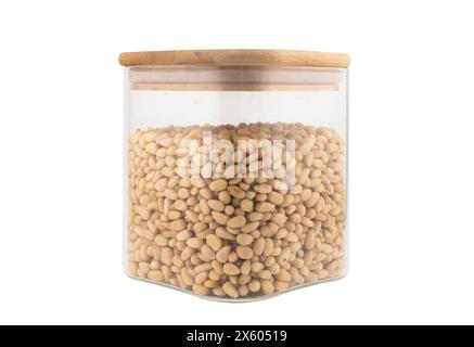 Cedar nuts in glass jar isolated on white background. Transparent glass package of pine nuts. Top view Stock Photo