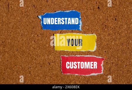 Understand your customer words written on ripped paper pieces with brown background. Conceptual understand your customer symbol. Copy space. Stock Photo