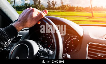 Male hands holding car steering wheel. Hands on steering wheel of a car driving. Young Man driving a car inside cabin. . Stock Photo