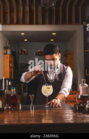 Expert bartender carefully adding a garnish to a crafted cocktail in a cozy bar setting Stock Photo