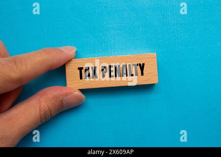 Tax penalty words written on wooden block with blue background Stock Photo