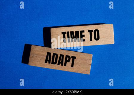 Time to adapt words written on wooden blocks with blue background. Conceptual time to adapt symbol. Copy space. Stock Photo