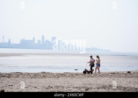 People walking dogs on New Brighton Beach on the Wirral, Merseyside. Picture date: Sunday May 12, 2024. Stock Photo