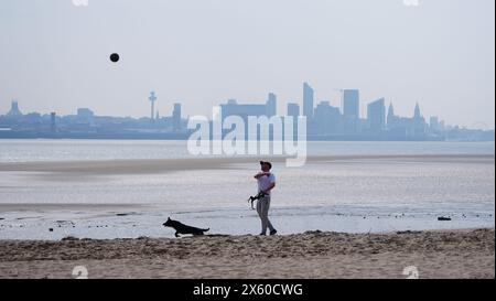 People walking dogs on New Brighton Beach on the Wirral, Merseyside. Picture date: Sunday May 12, 2024. Stock Photo