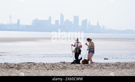 People walking dogs on New Brighton Beach on the Wirral, Merseyside. Picture date: Sunday May 12, 2024. Stock Photo