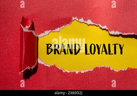Brand loyalty words written on ripped red paper with yellow background. Conceptual brand loyalty concept. Copy space. Stock Photo