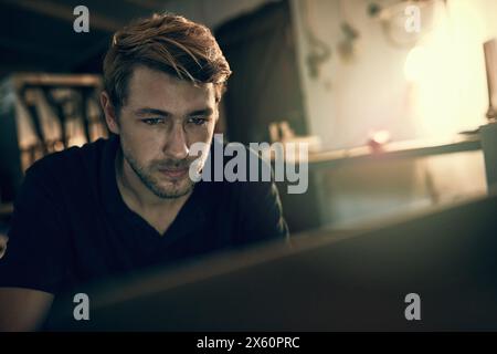 House, man and laptop with reading at night for freelance job, programming and online communication. Remote work, web design and developer with Stock Photo