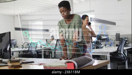 Image of month names and graph over african american woman working on blueprint in office Stock Photo