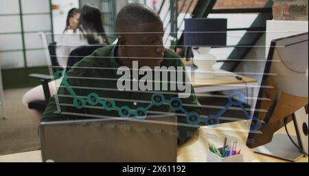 Image of graph over african american man working on computer in office Stock Photo