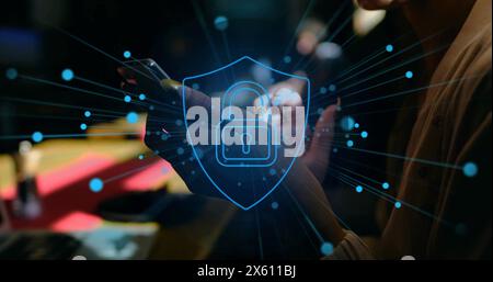 Image of padlock in shield over biracial woman scrolling on smartphone Stock Photo