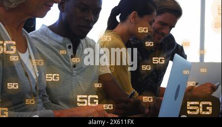 Image of multiple 5g texts over diverse coworkers working and using laptop in office Stock Photo