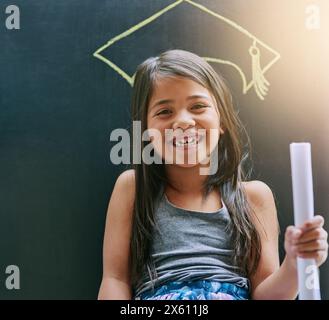 Portrait, little girl and blackboard with drawing, graduation cap and smile with daydreaming, school and happiness. Future, face and kid with degree Stock Photo