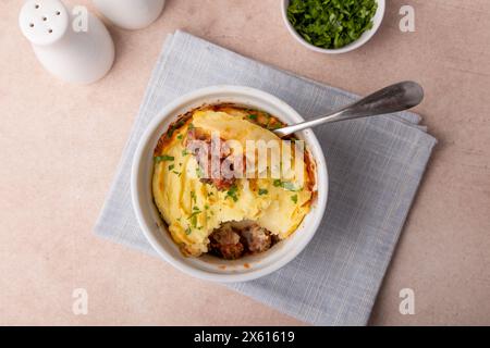 Shepherd's pie in a portioned white baking dish. Homemade traditional casserole (gratin) with minced meat and mashed potatoes. Selective focus, close- Stock Photo