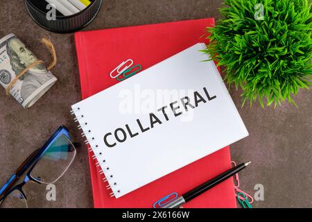 COLLATERAL text written on a blank sheet of notepad next to the business supplies Stock Photo