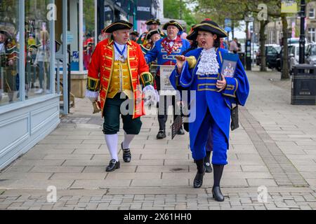 Town criers (bellmen & bellwomen in colourful braided crier's livery uniforms) walking & parading along The Grove - Ilkley, West Yorkshire England UK. Stock Photo