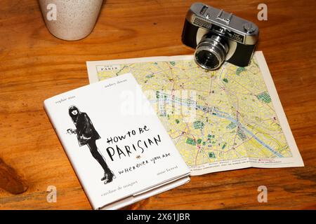 Book How to be a Parisian, wherever you are. By Sophie Mas, Audrey Diwan, Caroline de Maigret, Anne Berest. Themed on Paris map with vintage camera Stock Photo