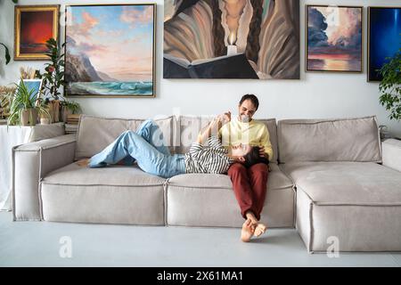 Happy painters couple resting on couch at home art studio. Woman, man loosening up on sofa together Stock Photo